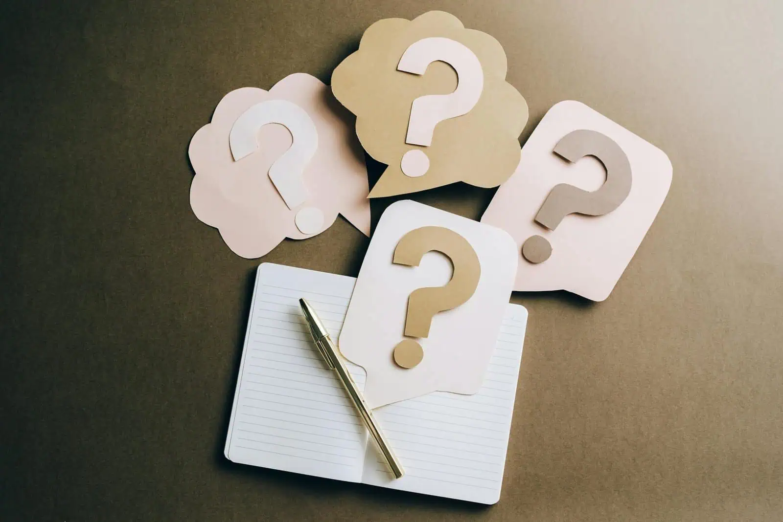 FAQ Flat lay of question mark paper crafts on a notebook, symbolizing questions and ideas.